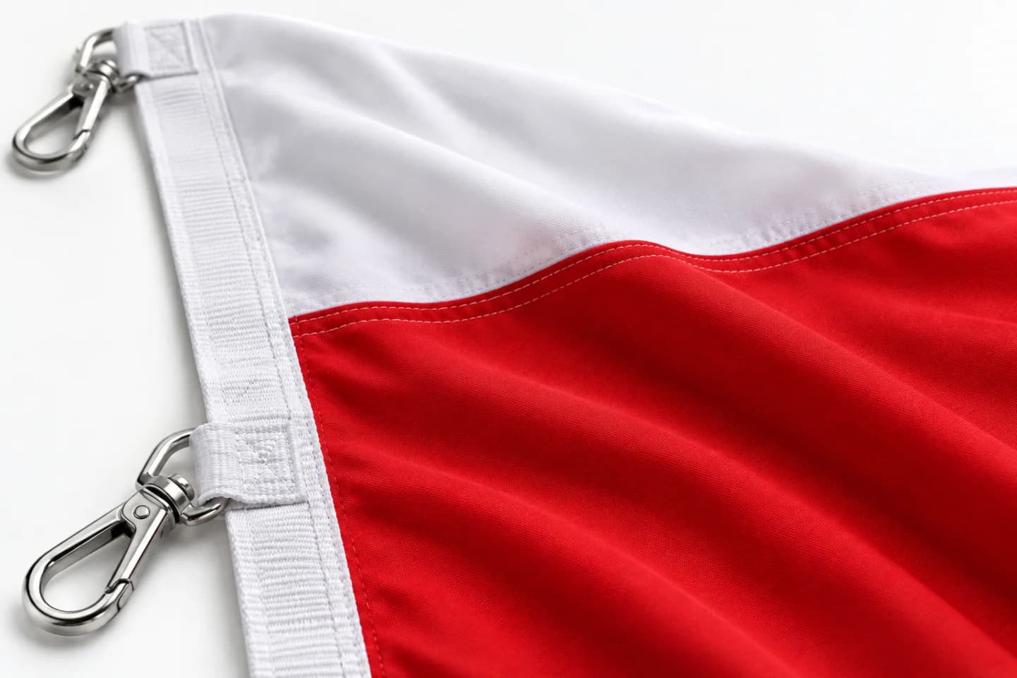 Detail látky bielo-červenej vlajky, obšitia a pásky s kovovou karabínou — ukážkové ušitie